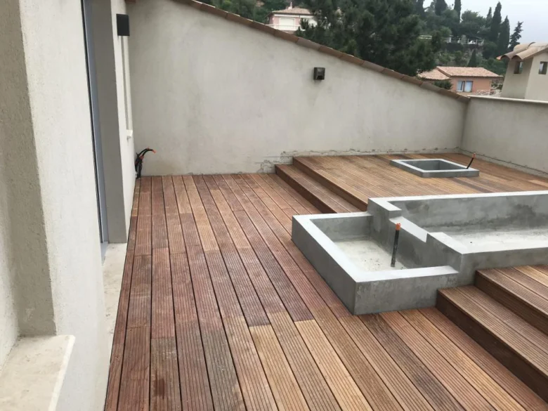 Vyvýšená dřevěná terasa s betonovými prvky na střeše.