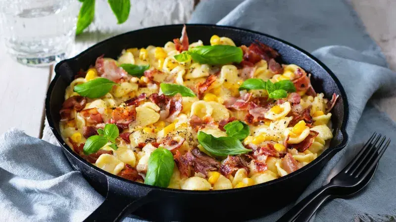 Pasta s kukuřicí a bazalkou v železném pánvi