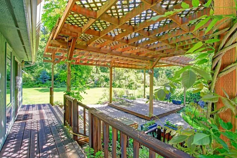 Dřevěná pergola s mřížkovou střechou na zahradě.