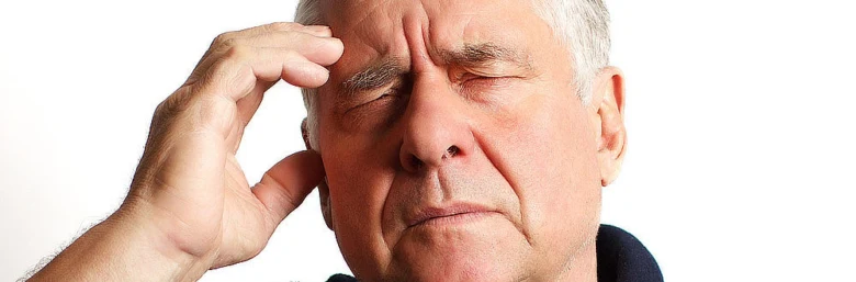 Starší muž drží hlavu kvůli bolesti hlavy nebo příznakům mrtvice.