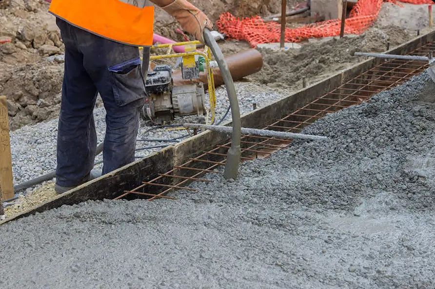 Stavebník nalévá beton do základové desky s výztuží.
