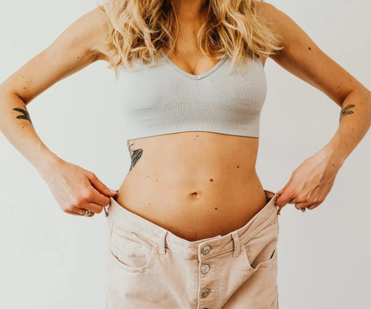 Žena s volnými kalhotami po zhubnutí hormonálního břicha.