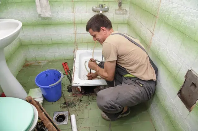 Muž renovuje koupelnu s odstraňováním staré vany.