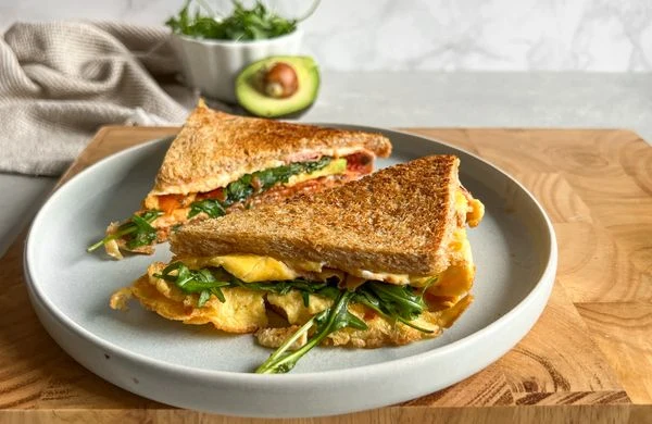 Slaný toast s vejcem a rukolou na talíři.