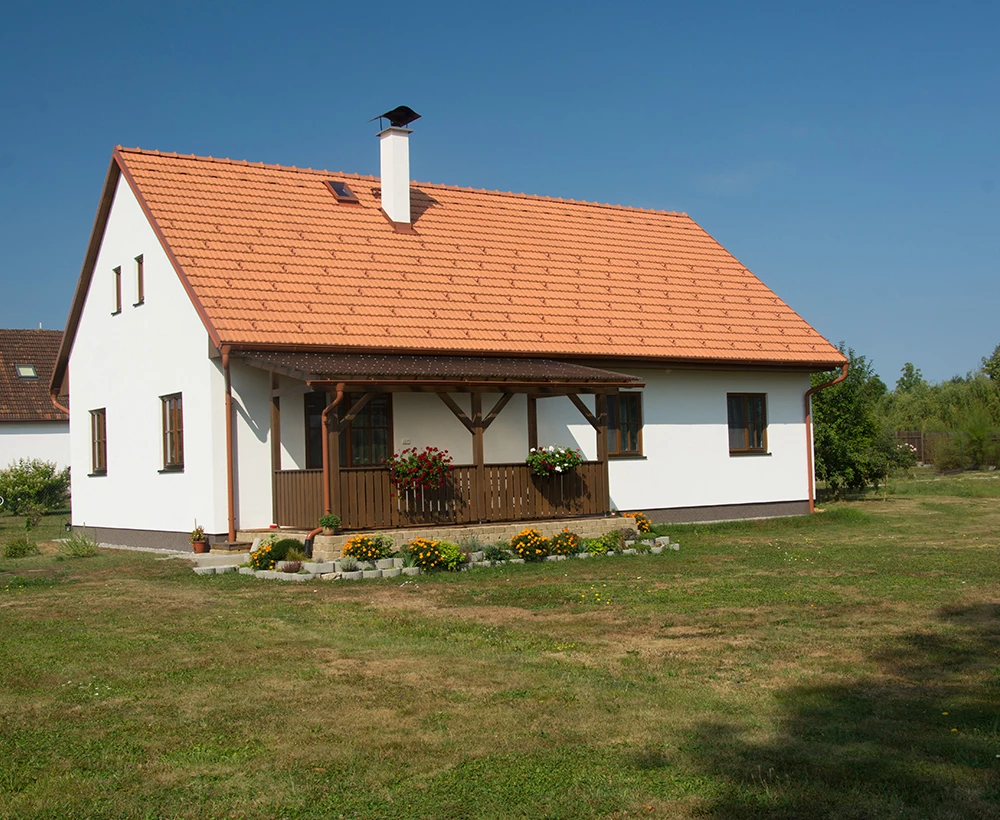 Dřevostavba s bílými stěnami na pozadí modré oblohy.