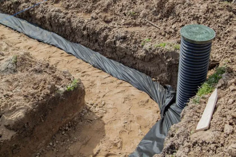Instalace drenážního systému s hadicí v příkopu.