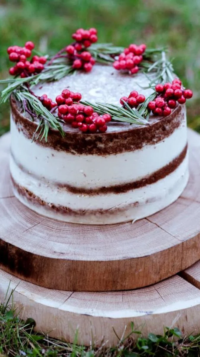 Vegan dort s jahodami, borůvkami a rozmarýnem na dřevěném podstavci.