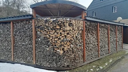Hotový dřevník z kari sítě pod střechou