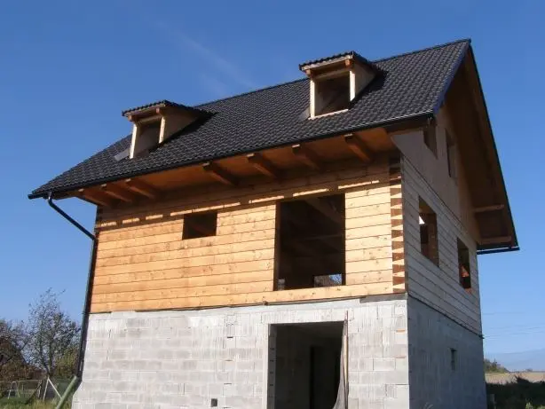 Dřevěný dům ve fázi stavby s viditelnou konstrukcí.