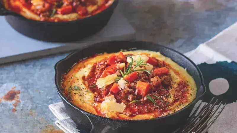 Kukuřičná polenta s masovou omáčkou v železném hrnci.