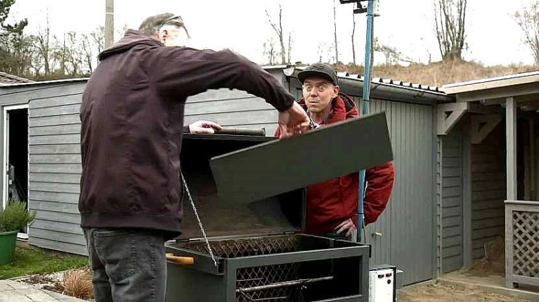 Muži sestavují gril z bojleru venku.