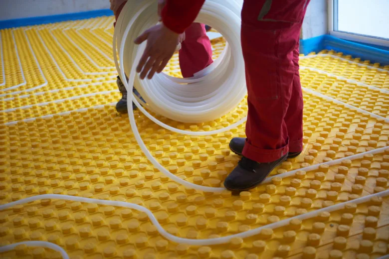 Instalace podlahového topení s bílými trubkami na žlutém podkladu