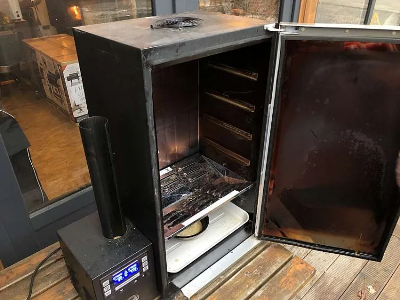 Elektrická udírna s otevřenými dveřmi pro kouření masa.