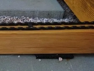 Detailní pohled na vyvýšenou dřevěnou terasu s kamínky.