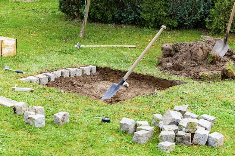 Výstavba ohniště v zemi s kameny a lopatami
