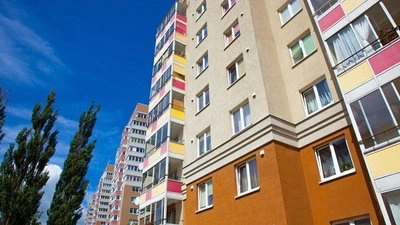 Moderní obytný dům s barevnými balkony pod modrou oblohou.