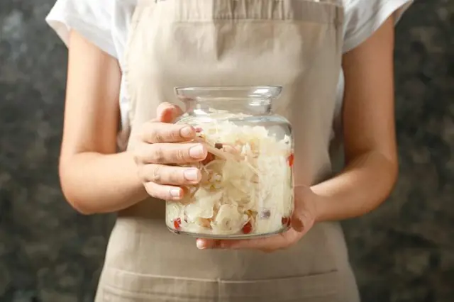 Person holding sauerkraut jar