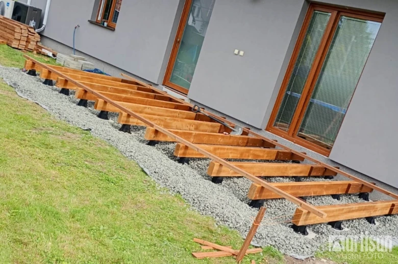 Rámování dřevěné terasy na plastových nohách nad štěrbinou.