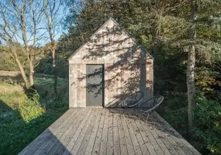 Moderní dřevěný dům v lese s terasou.