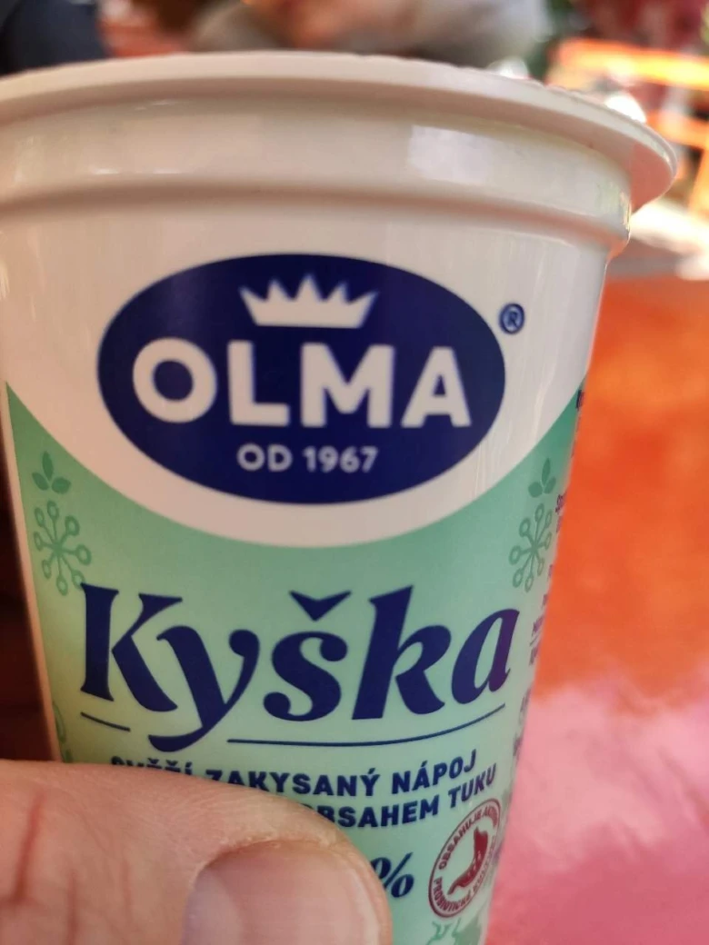 Bělejší zakysaný nápoj v poháru značky OLMA.