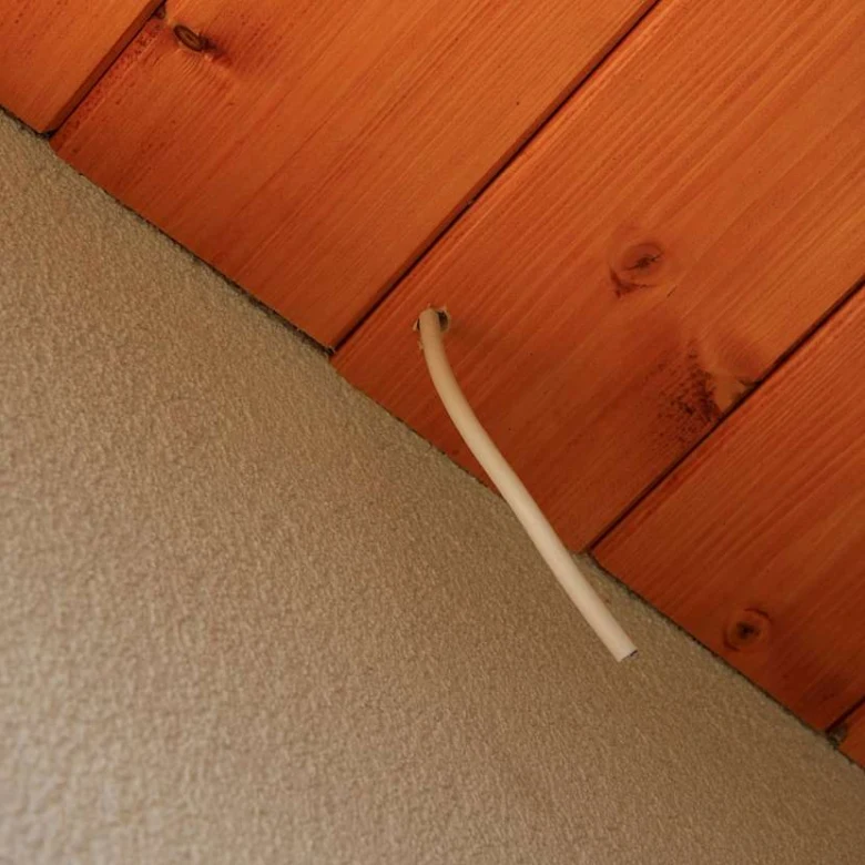 Bílý kabelový kanál v dřevěném stropu z palubek