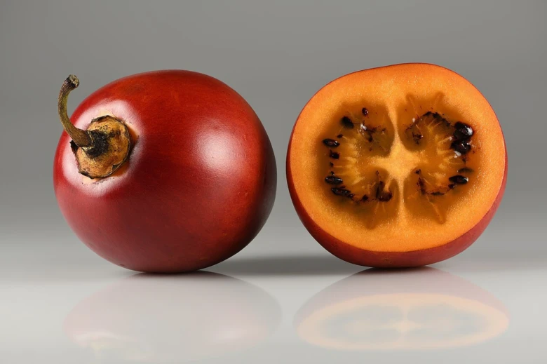 Celý červený tamarillo s řezem ukazující dužninu.