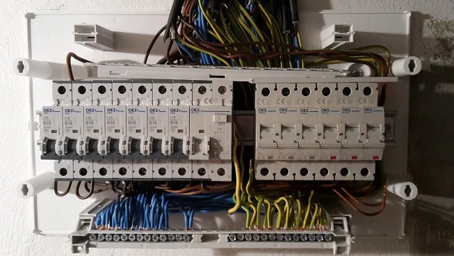 Otevřená elektrická rozvodnice s pojistkami a propojenými vodiči.