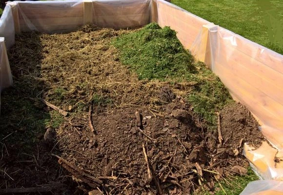 Výškový záhon s vrstvami kompostu a organických materiálů na dně