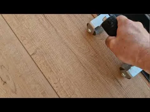 Ruka s nářadím pro instalaci dřevěné podlahy