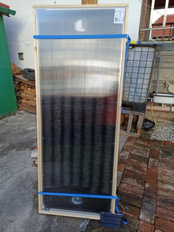 Domácí solární panel s dřevěným rámem a černými absorpčními trubkami