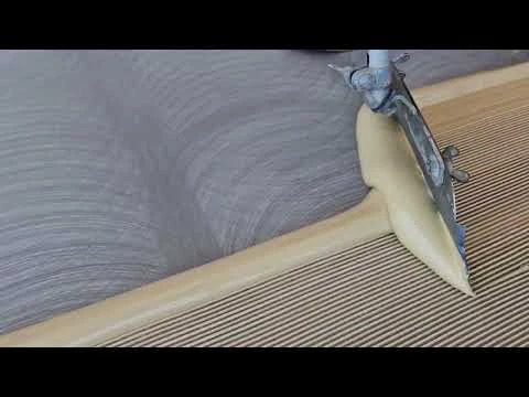 Nanášení lepidla na podlahu při instalaci topného roštu