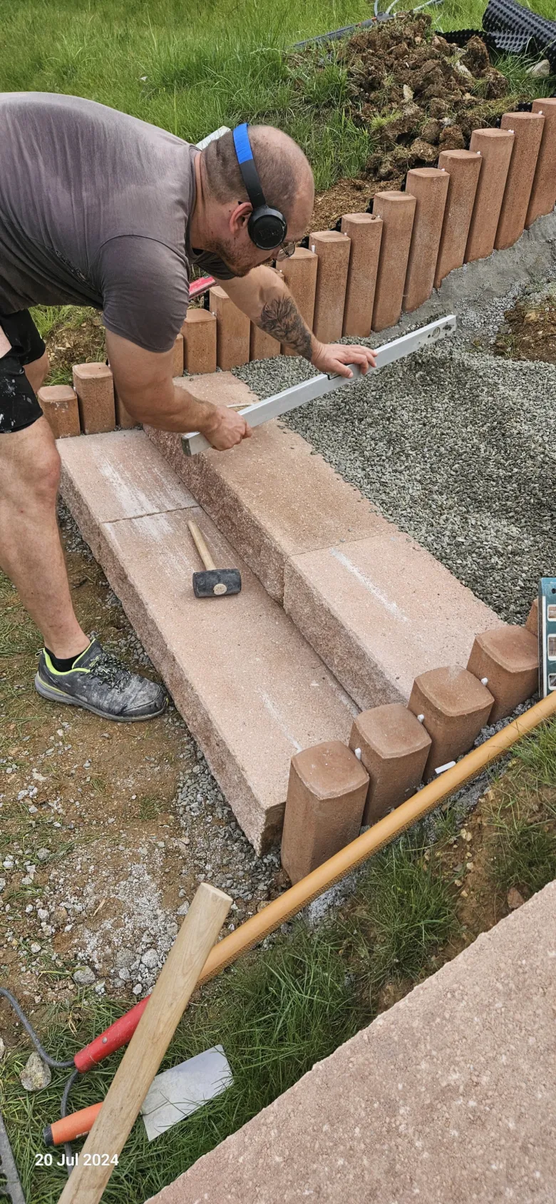 Muž staví venkovní betonové schody pomocí úrovně a kladiva
