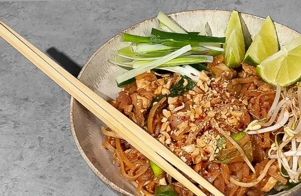 Mísa s pad thai, fazolovými klíčky a limetkami.