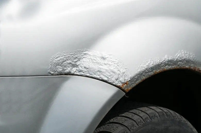 Bílý automobil s aplikovaným těsněním na povrchové korozi v kolovém oblouku.