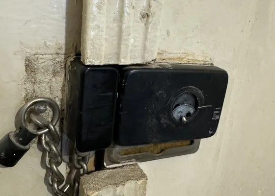 Zámek na dveřích s řetězem, typický pro službu zámečníka.