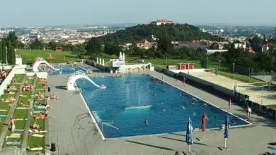 Venkovní plavecký areál s bazénem na kopci nad městem.