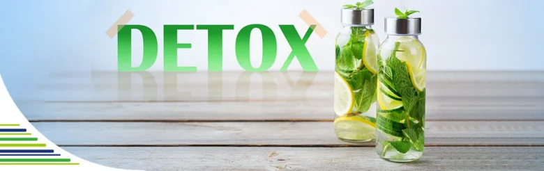 Dvě sklenice s detoxikující vodou, mátou, citronem a okurekou na dřevěném stole.