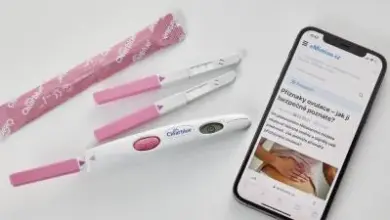 Ovulační testy s výsledkem vedle telefonu ukazujícího návod v češtině.