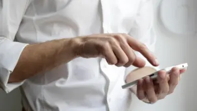 Muž v bílé košili používá chytrý telefon.