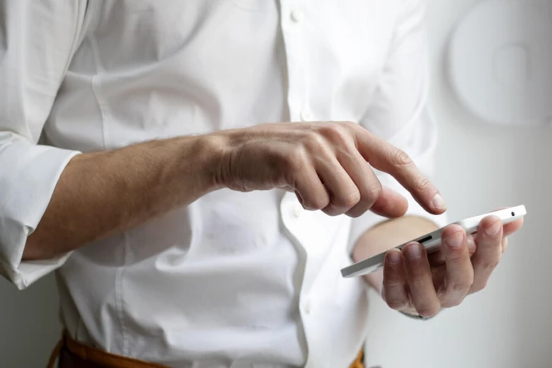 Muž v bílé košili používá chytrý telefon.