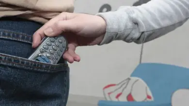 Ruka s mobilním telefonem v džínových kapsách.