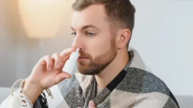 Muž používá nosní sprej do pravé nory.