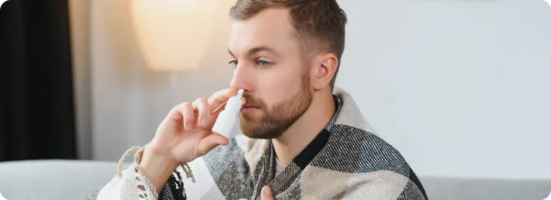Muž používá nosní sprej do pravé nory.
