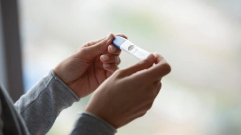Ruce drží ovulační nebo těhotenský test s modrým víčkem.