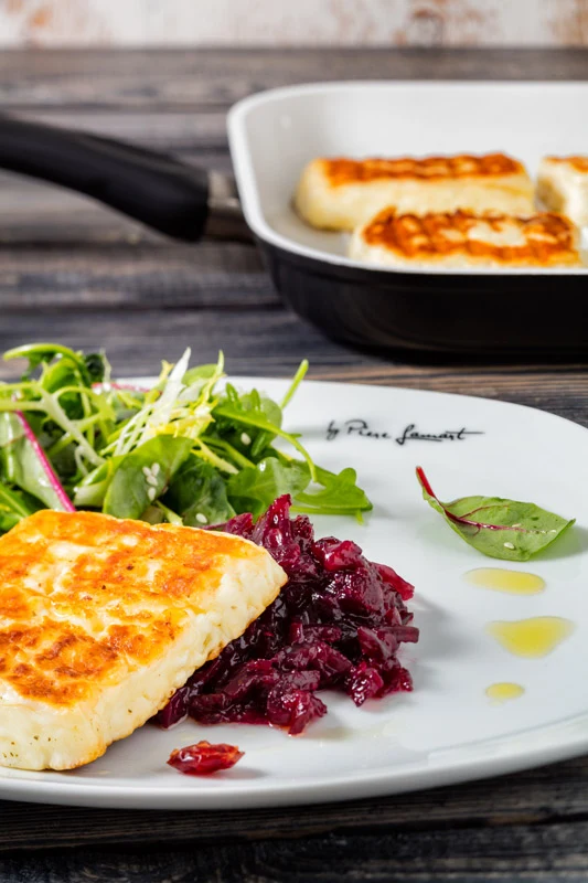 Grilovaný sýr Halloumi podávaný se salát a červeným ovocným omakem.