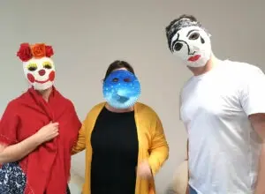 Tři lidé v tradičních českých masových maskách na pozadí.
