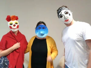 Tři lidé v tradičních českých masových maskách na pozadí.