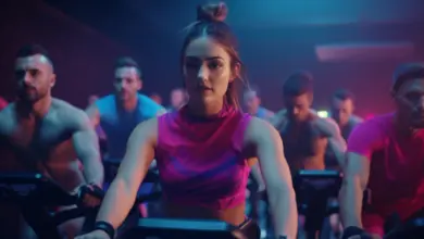 Žena vede spinning trénink s ostatními účastníky v posilovně.