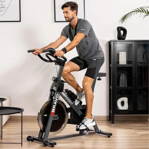 Muž cvičí na indoor bicyklu v interiéru.