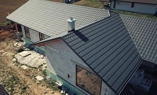 Střecha domu ve fázi stavby s šedými taškami.